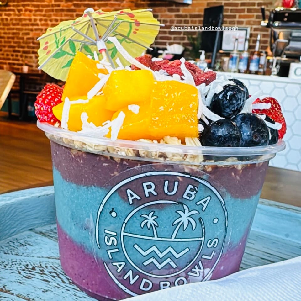 Aruba Island Bowls Cafe acai bowl with mango, blueberries, raspberries, and a tiny umbrella.