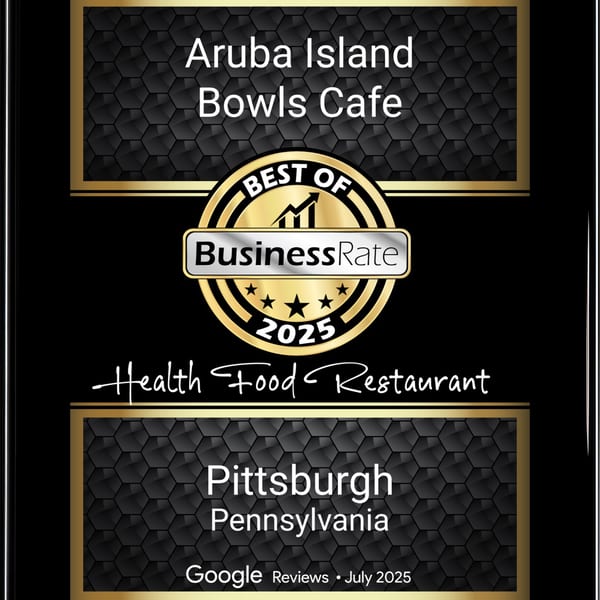 A black and gold award plaque for Aruba Island Bowls Cafe, Best Health Food Restaurant 2025.